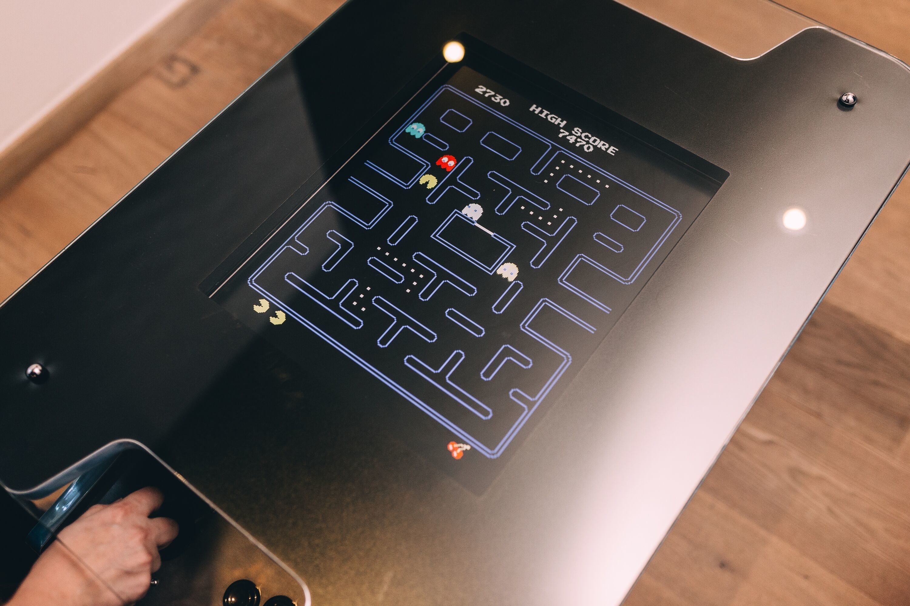 A digital game interface on a black surface with a hand interacting with it.