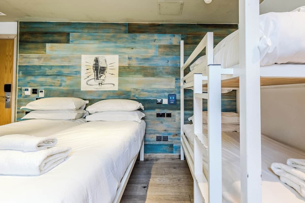 Habitación con literas, pared de madera azul, un cuadro y un enchufe.