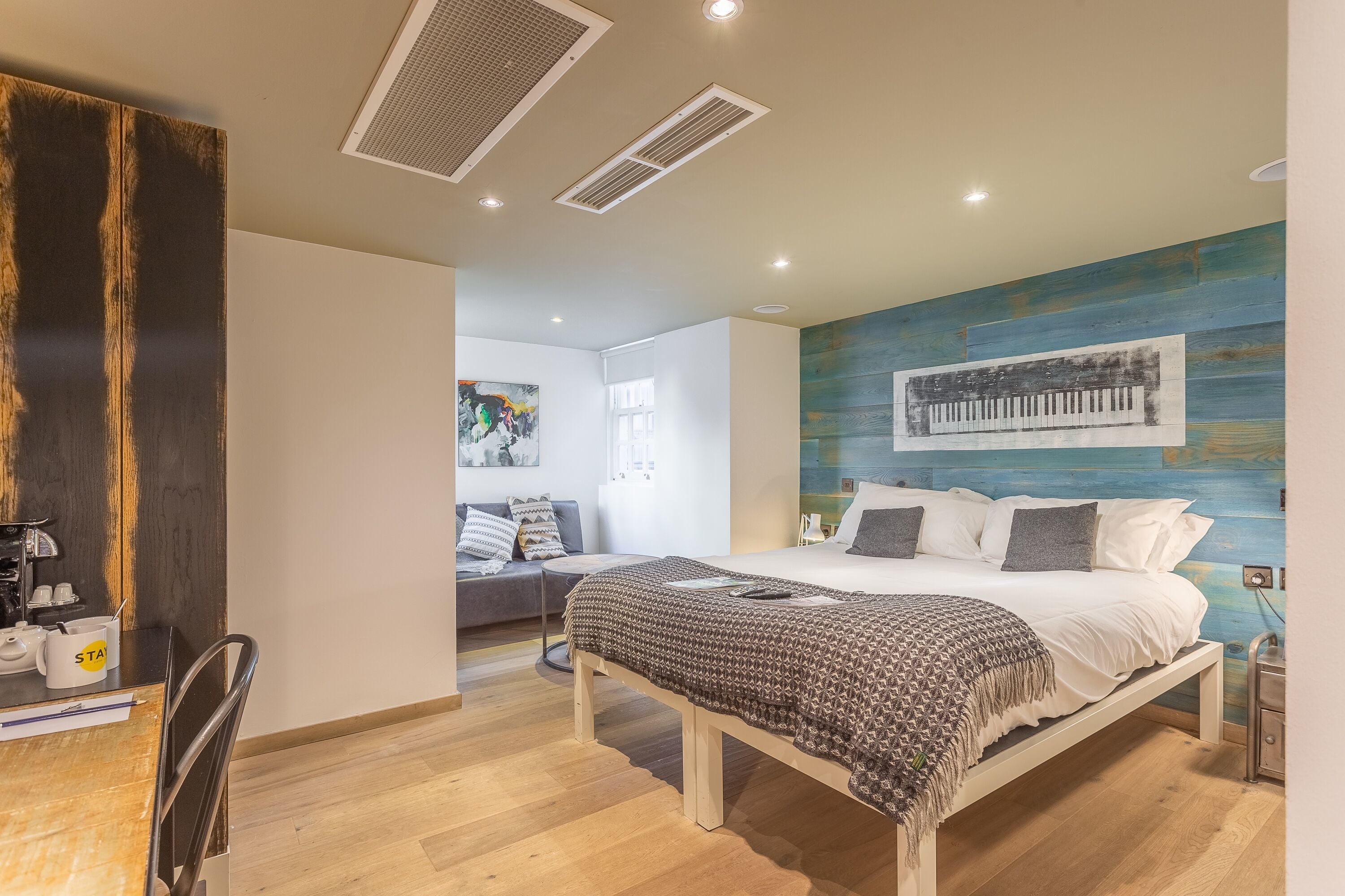 Un dormitorio moderno con cama, mesita de noche e imagen de un piano montado en la pared.