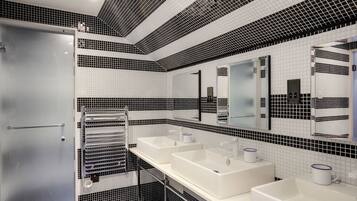 A modern bathroom with two sinks, a large mirror, and a towel rack.