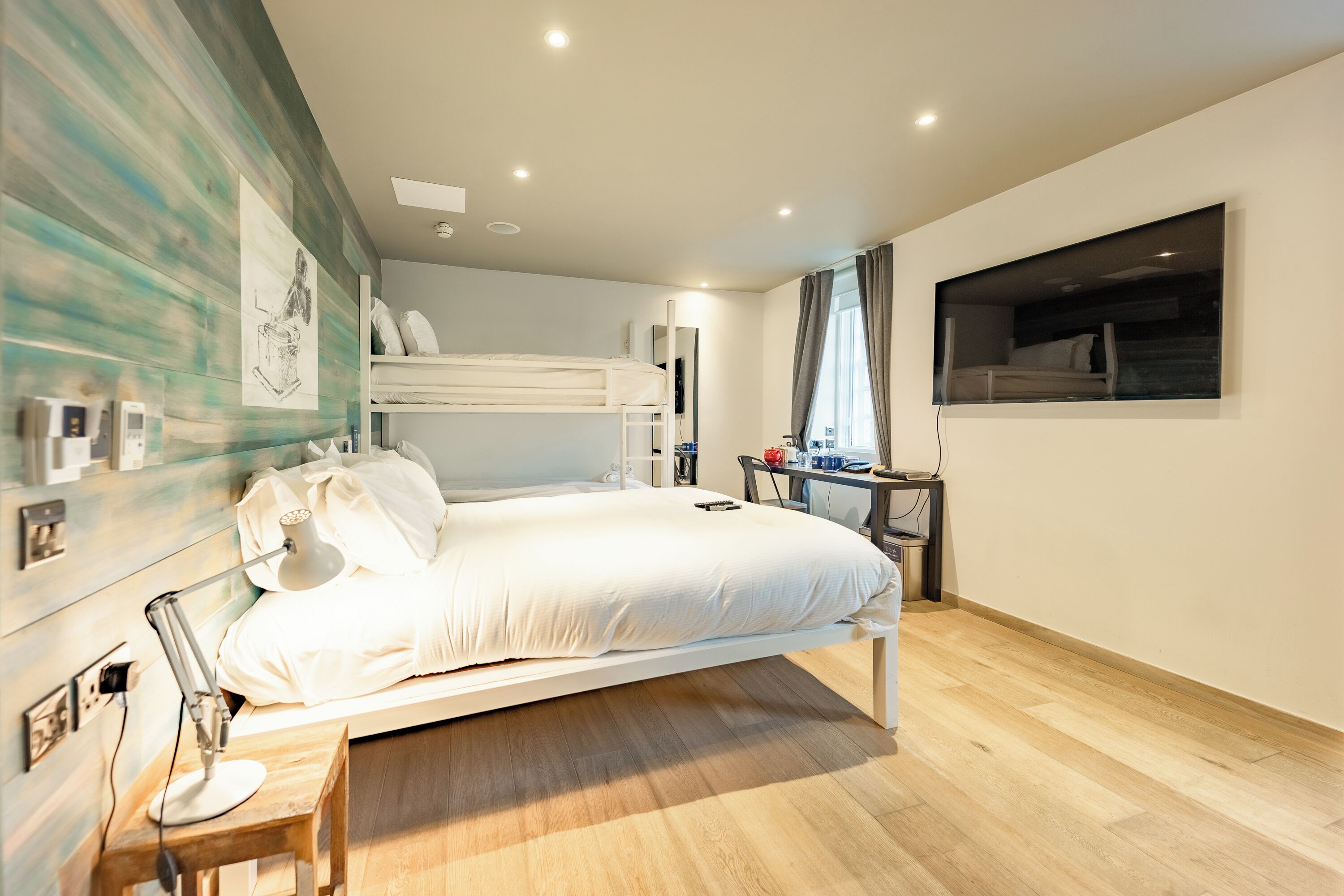 Un dormitorio moderno con una cama litera, un escritorio y un ventanal grande.