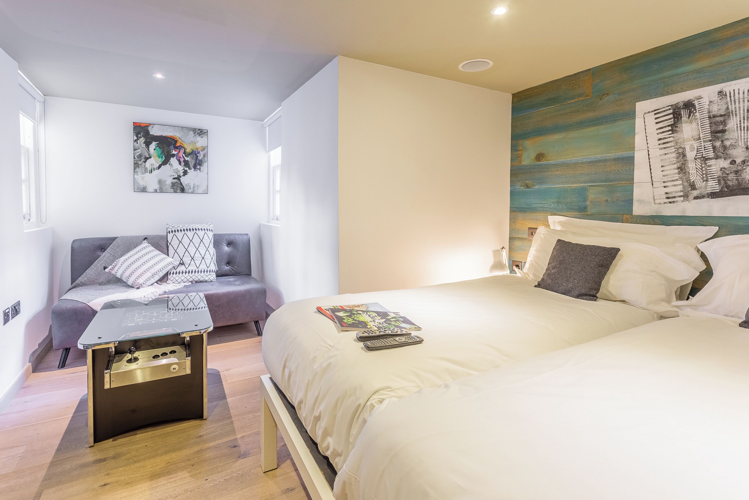 Une chambre moderne avec un lit, un canapé et une petite table sur laquelle se trouve une lampe.