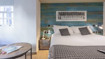Une chambre d’hôtel avec un lit, une table de chevet, une lampe et une fenêtre avec des stores.