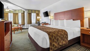 A hotel room with a large bed, a desk, a chair, a TV, and a ceiling fan. - Best Western Liberty Inn (Delano)