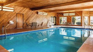 An indoor swimming pool with wooden walls and ceiling, surrounded by lounge chairs and a covered seating area. - Best Western Liberty Inn (Delano)