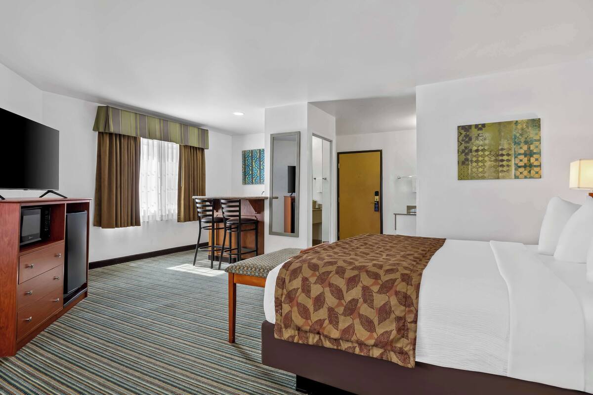 A hotel room with a bed, a desk, a television, and a mirror.