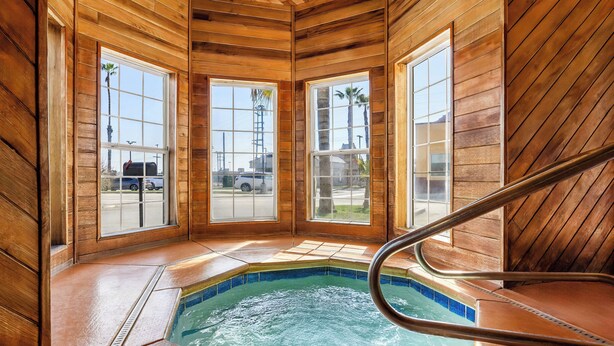 A wooden interior with a hot tub, large windows, and a view of the outside. - Best Western Liberty Inn (Delano)