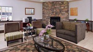 A hotel lobby with a stone fireplace, two sofas, a coffee table, and a striped bench. - Old Mill Inn (Omaha)