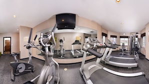 A gym with cardio machines, weight equipment, and a mirrored wall. - Old Mill Inn (Omaha)