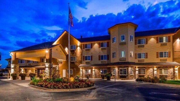 A multi-story hotel with a stone facade, multiple windows, and a flagpole. - Old Mill Inn (Omaha)
