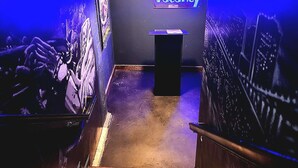 A staircase leading to a room with a neon sign reading "No Vaccination" and a cityscape mural on the wall. -  Aiden San Antonio Riverwalk (San Antonio)