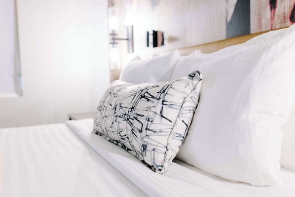 A neatly made bed with white linens and a pillow with a black abstract pattern. - Aiden San Antonio Riverwalk (San Antonio)