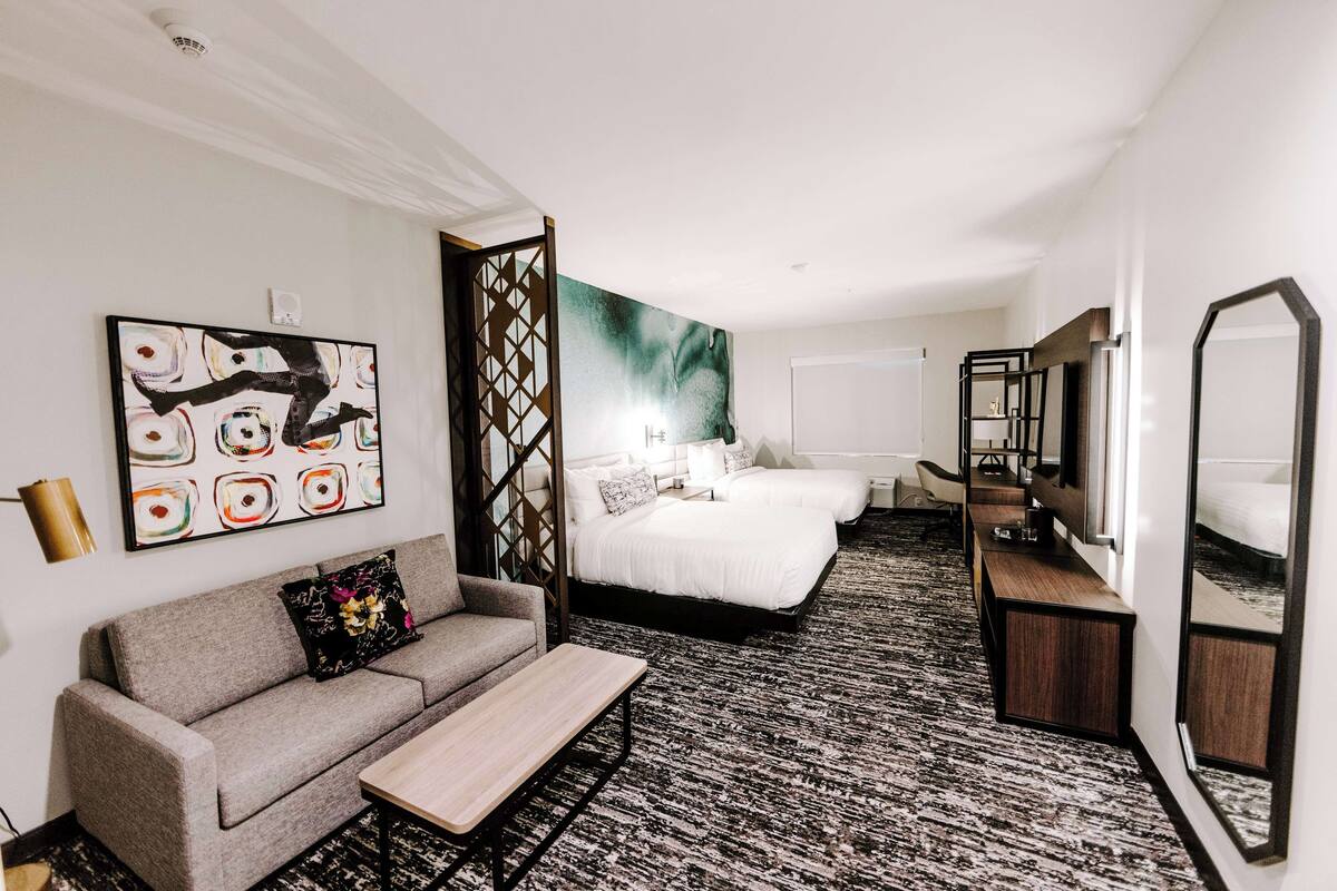 Une chambre d’hôtel avec un canapé, un lit, un bureau et un grand miroir.