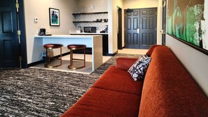 A modern living room with a red sofa, a kitchen area with a bar, and a large painting on the wall. -  Aiden San Antonio Riverwalk (San Antonio)