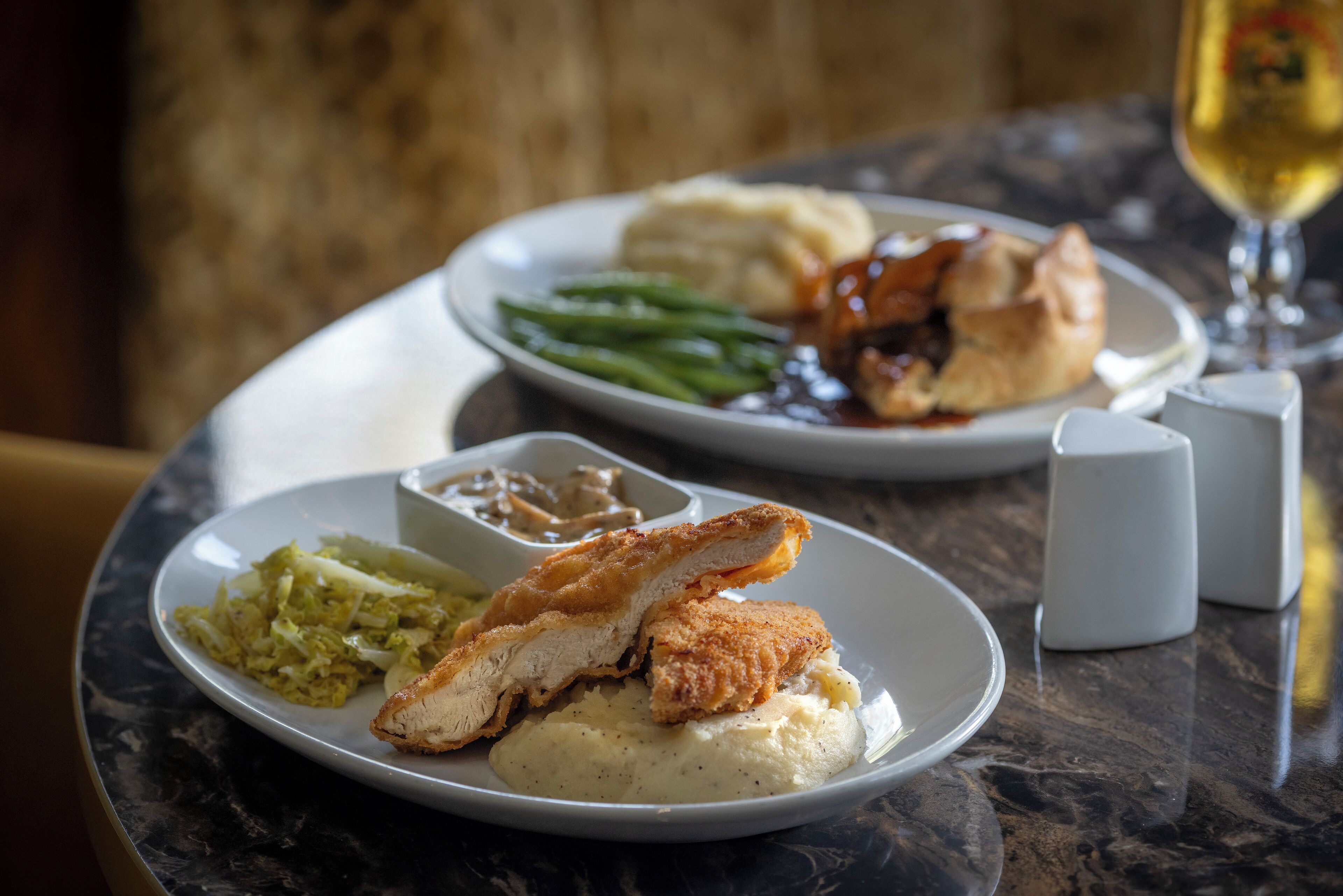 A dining table with plates of food, including a fish fillet, mashed potatoes, and green beans.