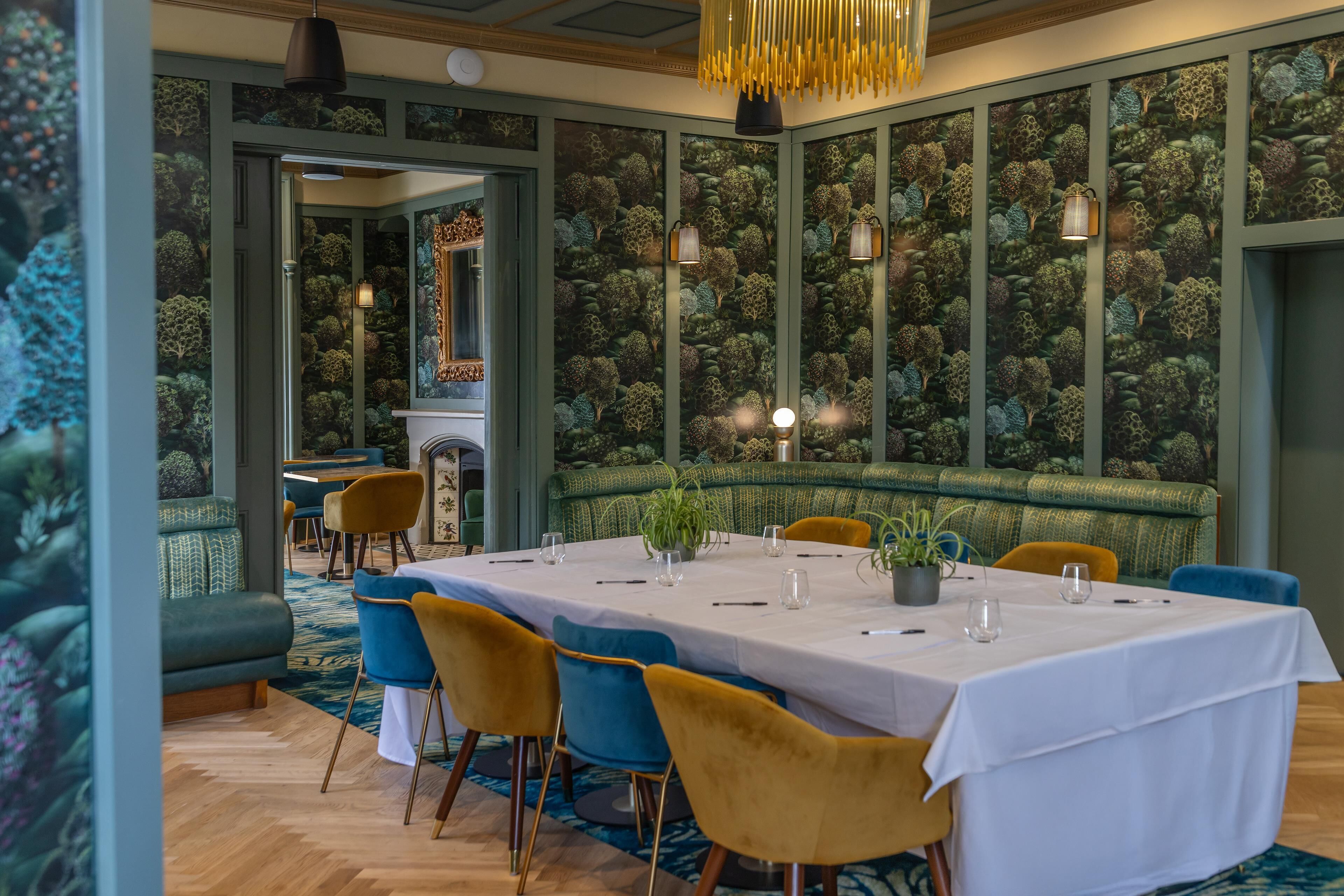 Un comedor con una mesa larga, sillas y un muro con diseño.