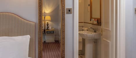 A hotel room with a bed, a large mirror, and a bathroom with a sink and mirror.
