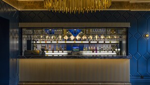 Un espace bar avec un comptoir, des étagères remplies de bouteilles et un écran de télévision.