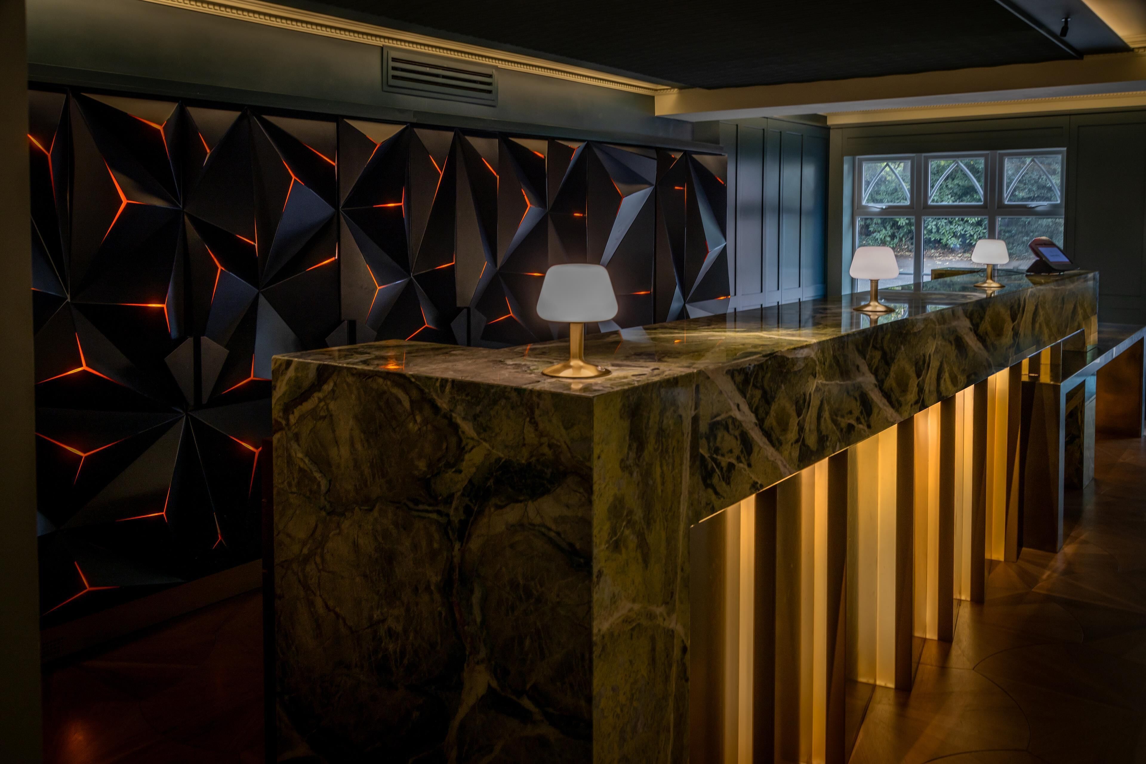 A modern bar area with a marble countertop, geometric wall design, and ambient lighting.
