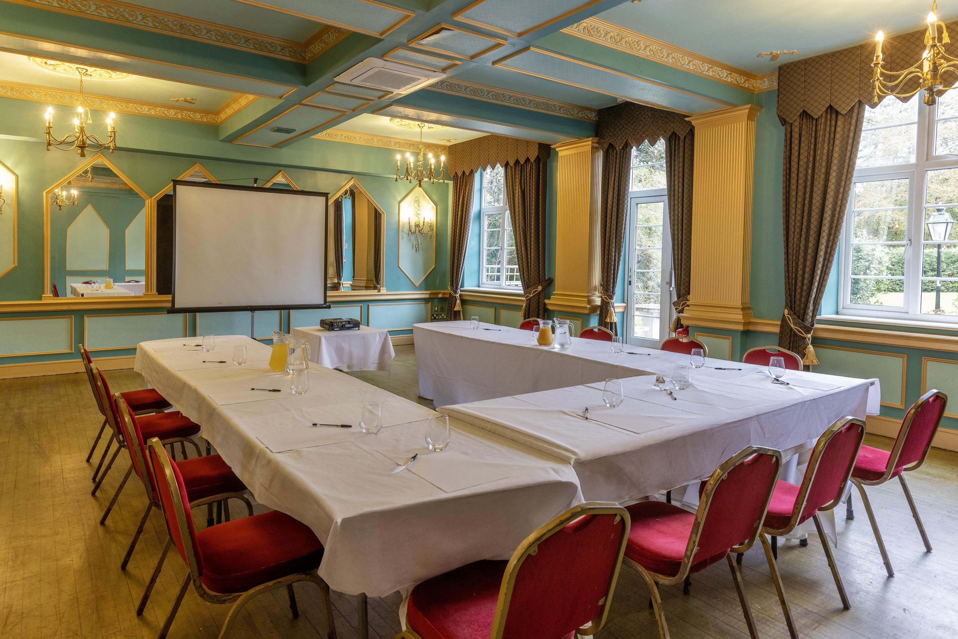 A conference room with multiple tables, red chairs, and a whiteboard.