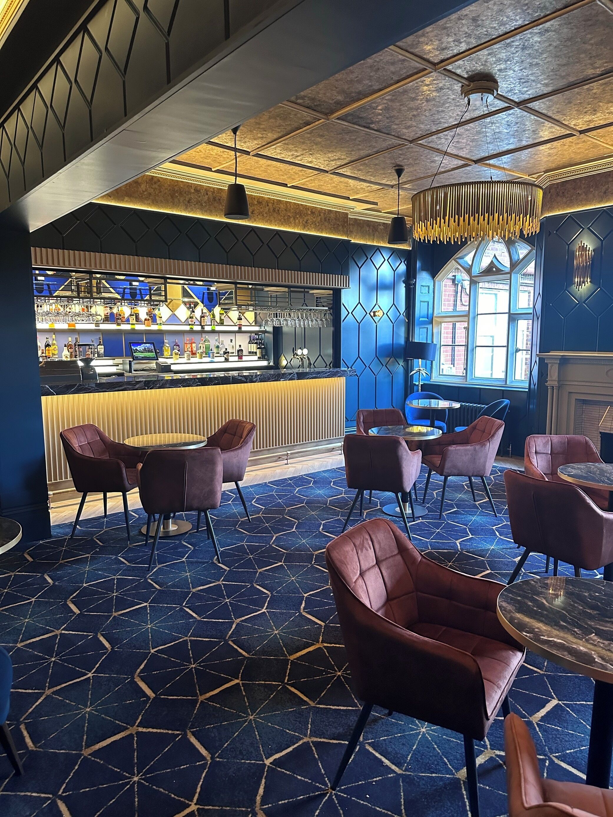 Una zona de bar con mostrador, asientos y una alfombra estampada.