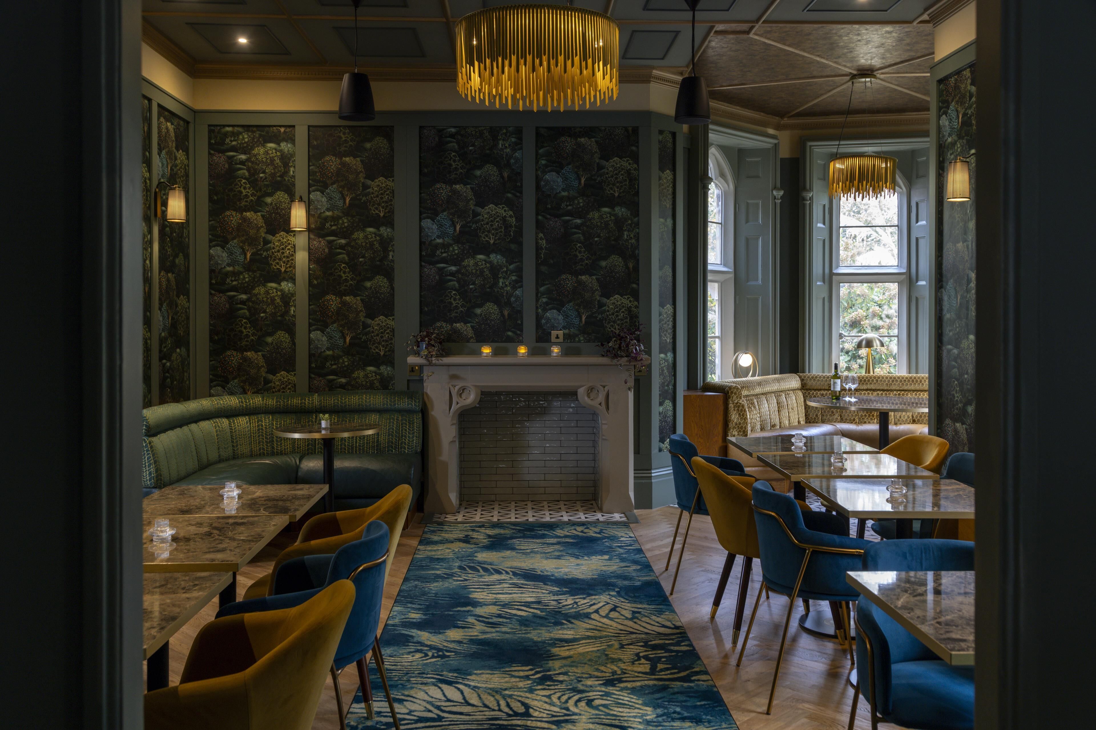 A restaurant with a fireplace, seating areas, and a patterned wall.