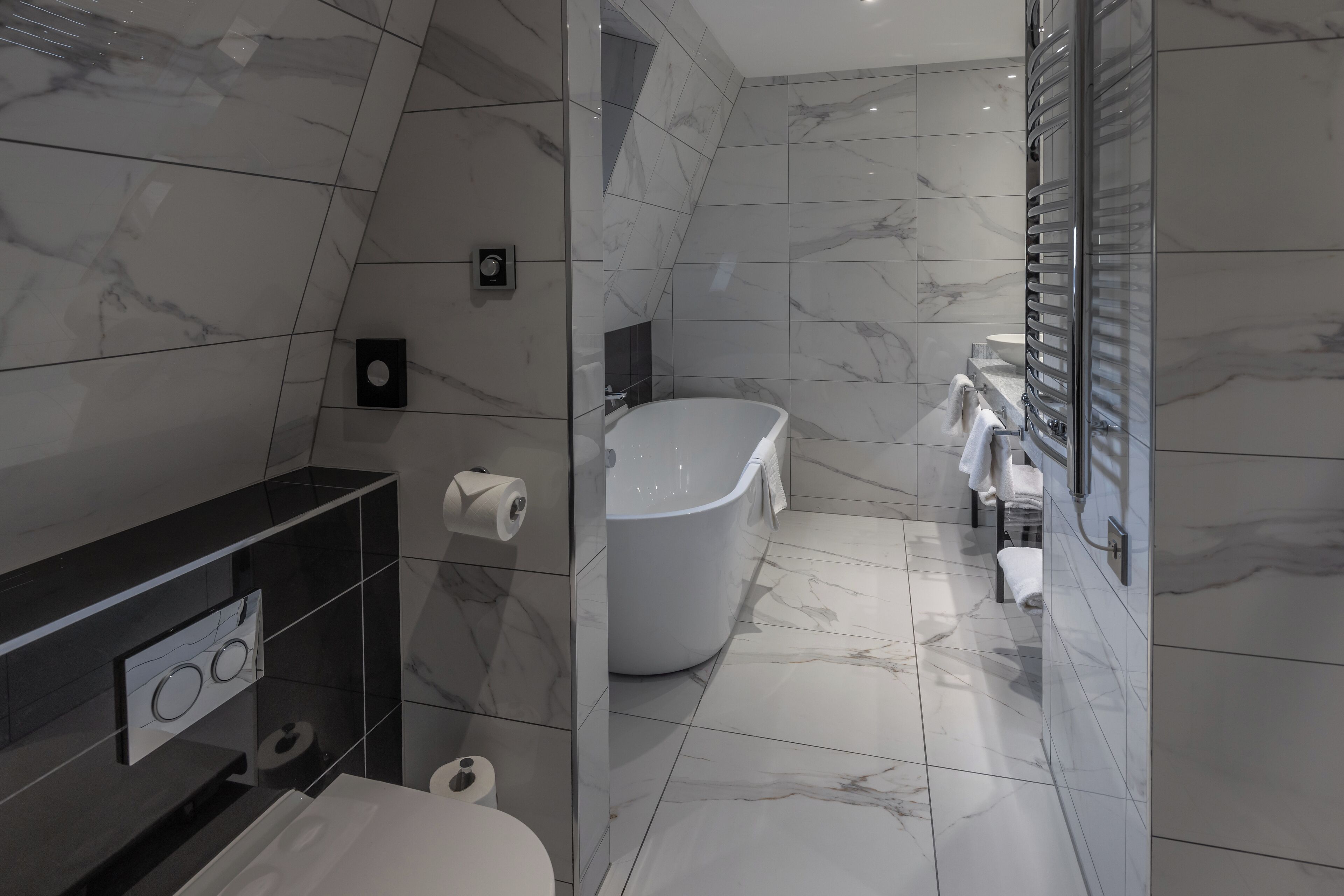 Un baño moderno con una bañera independiente, inodoro y tocador con espejo.