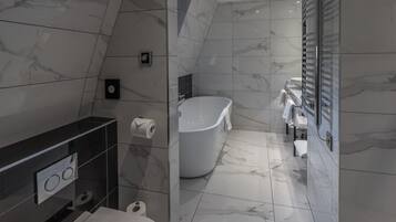 Un baño moderno con una bañera independiente, inodoro y tocador con espejo.