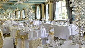 A banquet hall with multiple round tables set for a formal event, each with white tablecloths, gold sashes, and crystal centerpieces. - Best Western Abbots Barton Hotel (Canterbury)