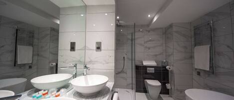 A modern bathroom with two sinks, a shower, and a toilet.