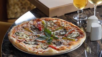 A pizza with various vegetables on a marble table.