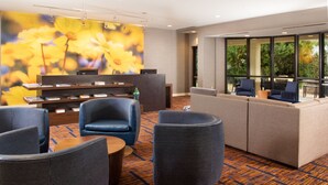 A hotel lobby with a reception desk, seating area, and large windows offering a view of the outdoors.