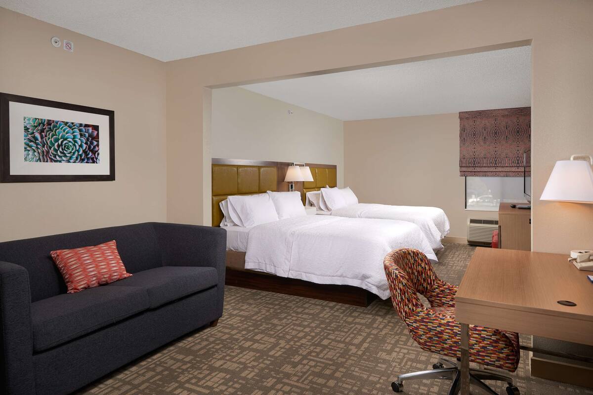 A hotel room with a bed, a sofa, a desk, and a chair.