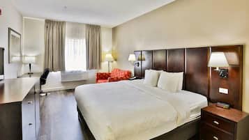 Habitación de hotel con una cama grande, lámparas de noche, un escritorio con silla y una ventana con cortinas.