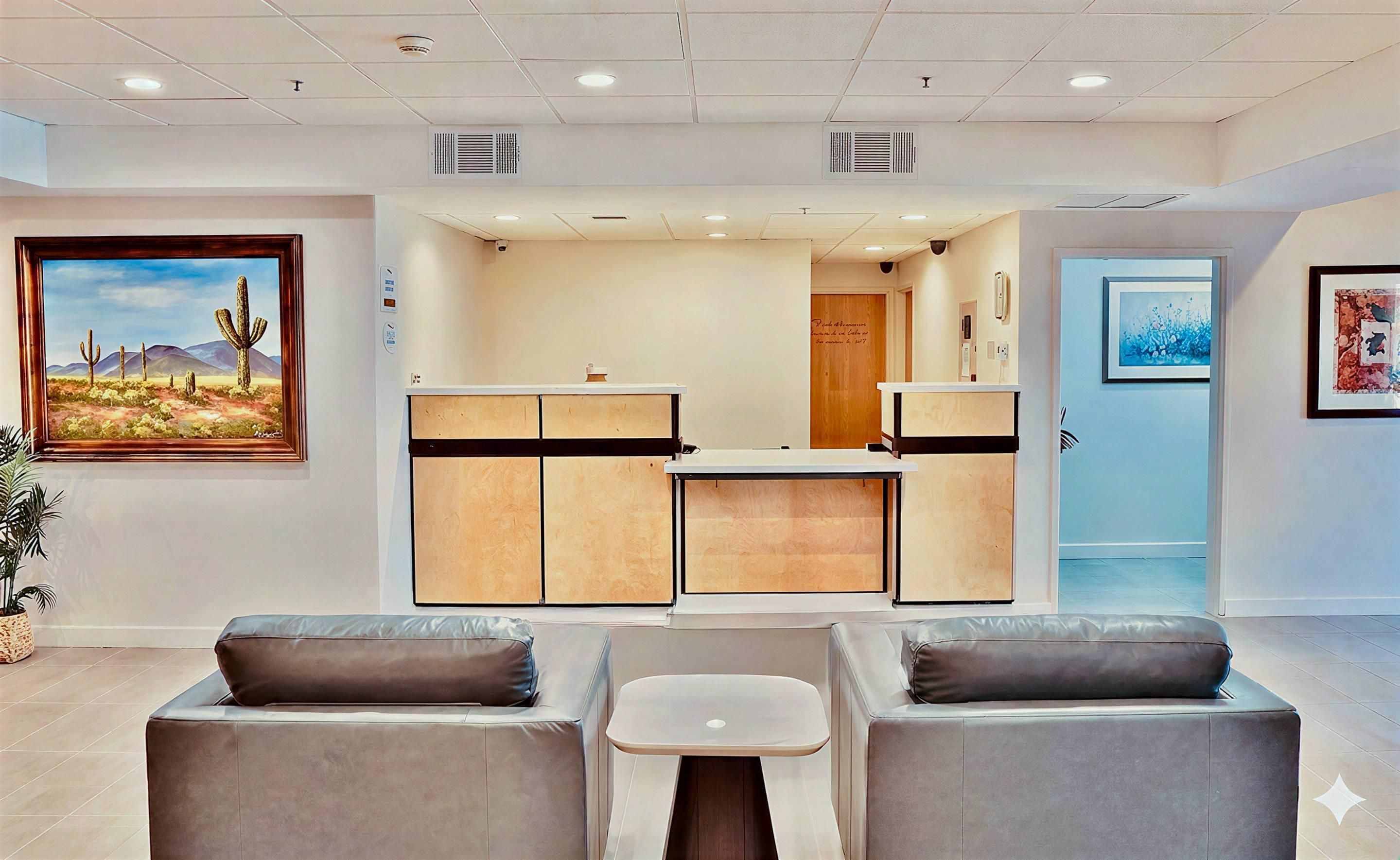A reception area with a desk, two sofas, a painting, and a door.