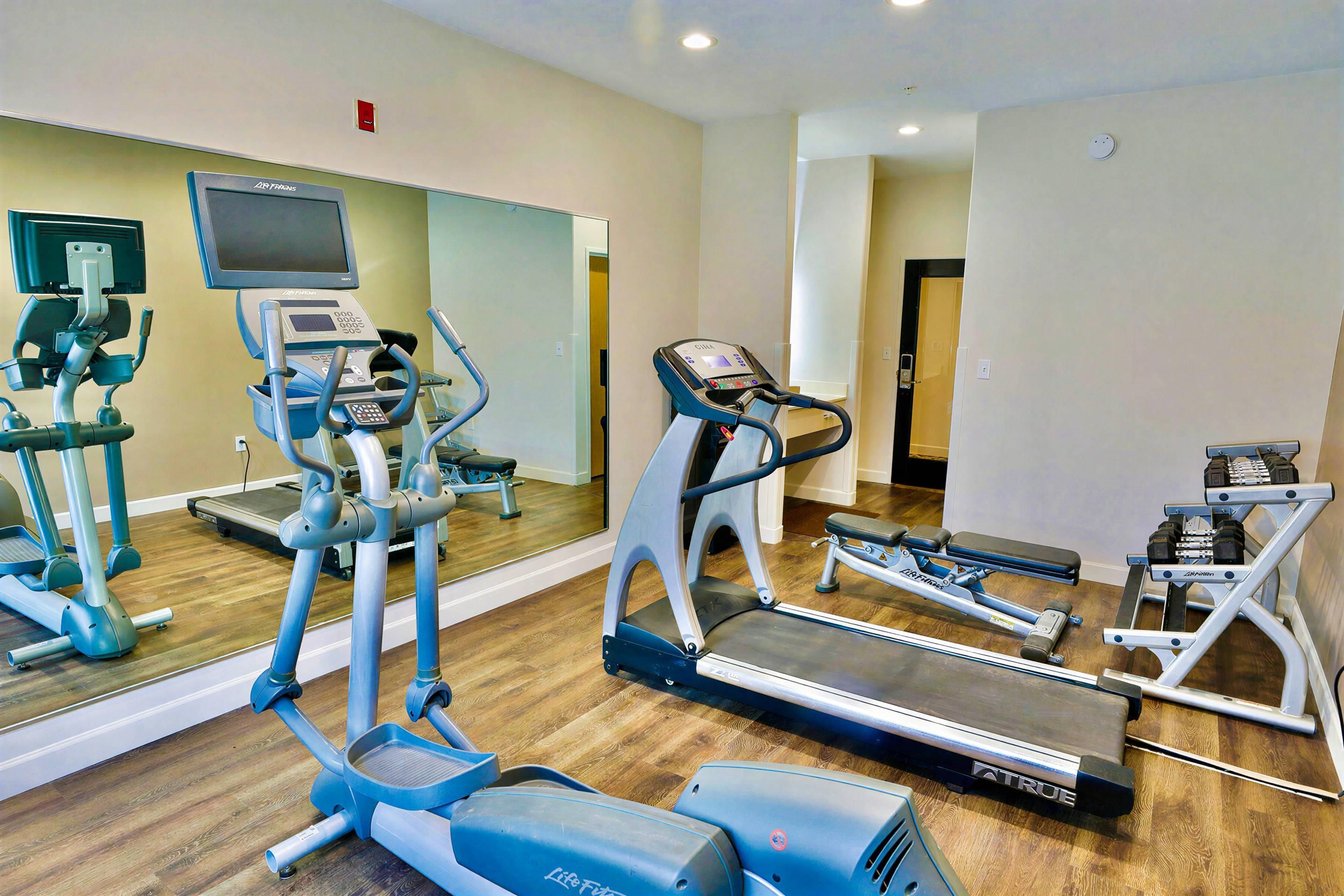 A gym with treadmills, elliptical machines, and weight equipment.