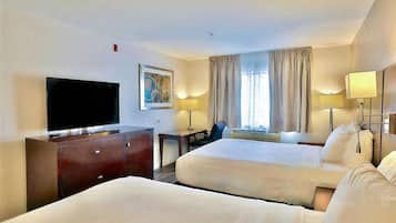 Una habitación de hotel con dos camas, televisión, escritorio y una silla.