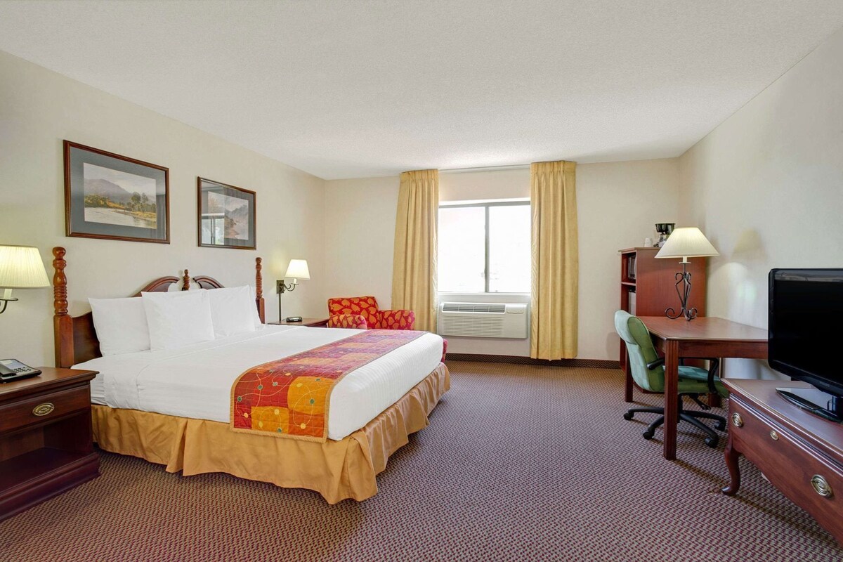 A hotel room with a bed, desk, television, and two lamps.