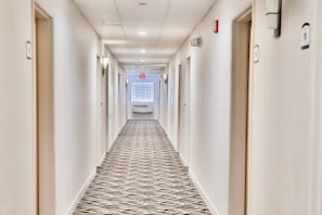 A hotel hallway with carpeted floors, doors on both sides, and an exit sign at the end. - Comfort Inn & Suites - Tucson Airport (Tucson)