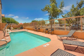 A swimming pool with lounge chairs and a fence, surrounded by trees and buildings. - Comfort Inn & Suites - Tucson Airport (Tucson)