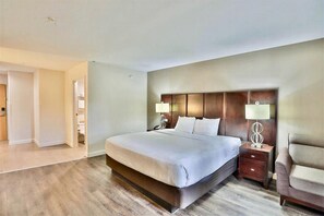 Habitación de hotel con una cama grande, mesitas de noche con lámparas, cabecero de madera y suelo de madera.