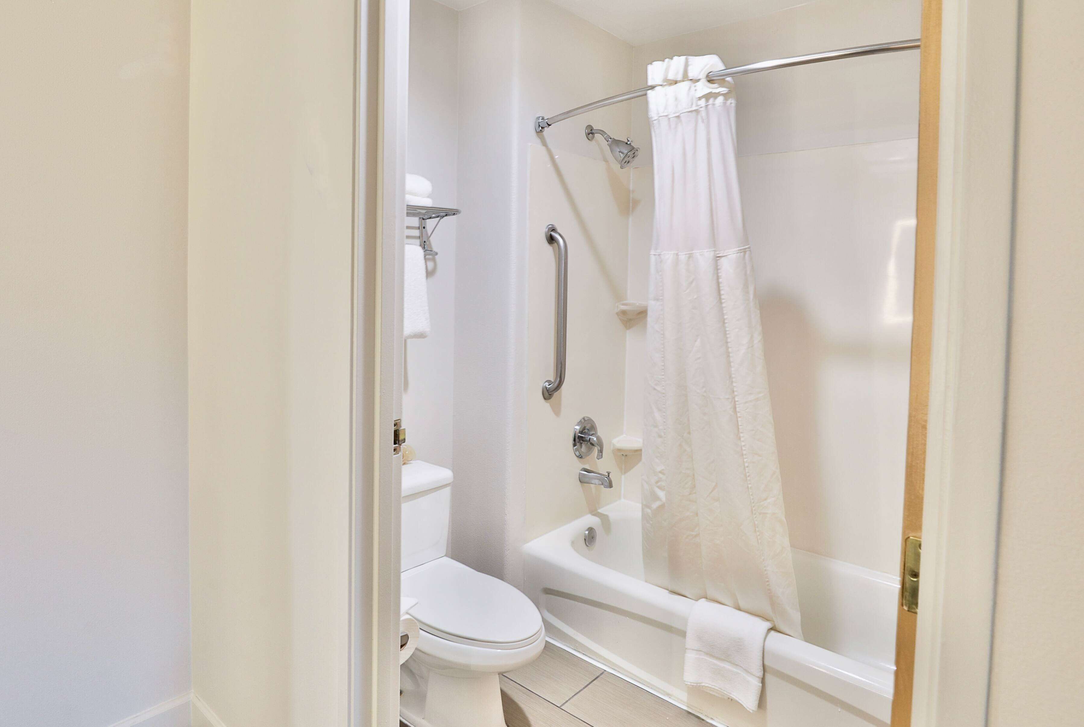 Un baño con inodoro, ducha con puerta de vidrio y bañera.
