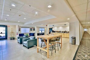 Un vestíbulo de hotel con zona de estar, kitchenette y un pasillo.