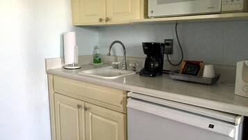 A compact kitchen with a microwave, coffee maker, and a sink.