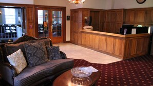 A lobby with a wooden reception desk, a patterned sofa, and a chandelier. - Boulder Dam Hotel (Boulder City)