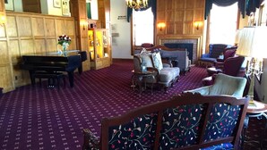 A room with a piano, a sofa, and a fireplace. - Boulder Dam Hotel (Boulder City)