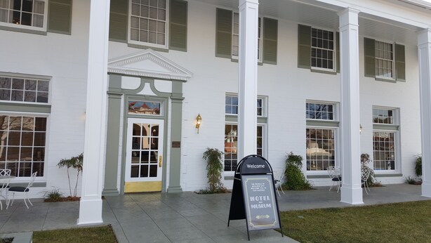 A historic building with a white facade, green shutters, and a central entrance with a pediment. - Boulder Dam Hotel (Boulder City)