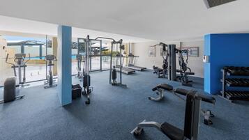 A gym with cardio machines, weightlifting equipment, and dumbbells.