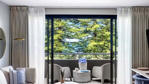 Un salon moderne doté d’une grande fenêtre, d’un canapé, d’une table basse et d’un balcon avec un espace salon extérieur.