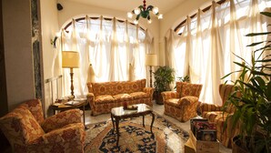 A living room with a patterned sofa, armchairs, a coffee table, and a potted plant. - Alla Rocca Hotel (Valsamoggia)